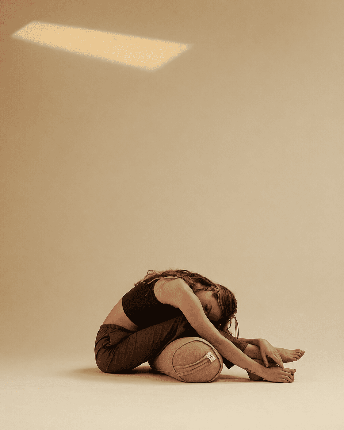 Person sitting on the floor with head in hands against a plain wall.